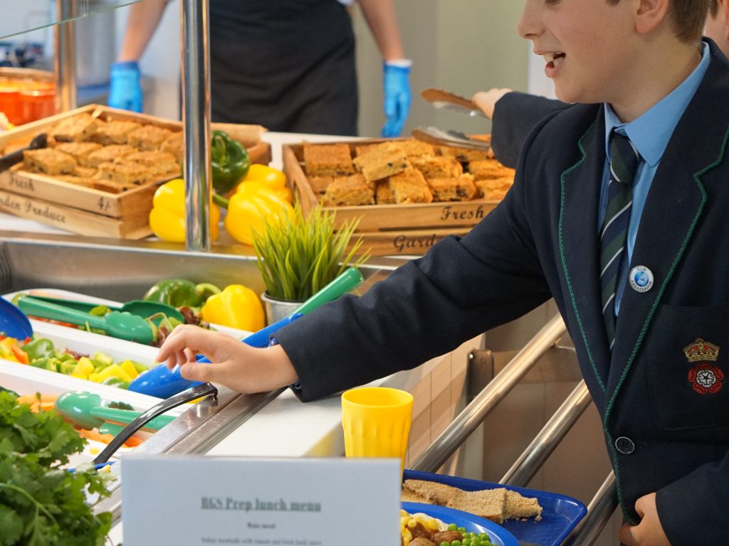 Student grabbing food to put on his plate