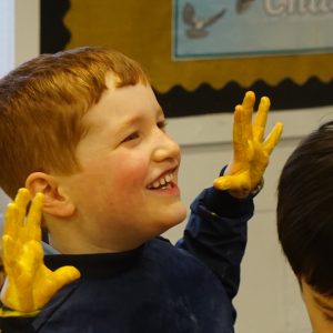 student with hands caked in yellow paint