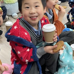 child holding a cookie and a hot drink