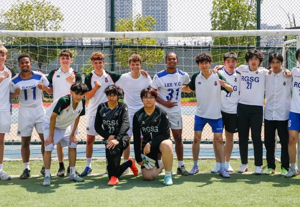 Youth soccer team posing for a group photo on a sunny field in front of a goal netz behind them